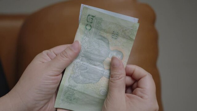 Thai baht banknotes, Woman's hands hold money. THB is official currency of Thailand. Finance and banking business in Asia, Weak baht impact of global economy from virus.