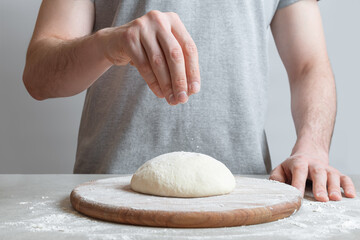 The process of making margarita pizza. Male hands, top view. Tomato paste with cheese.