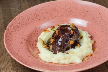 Baked veal cheeks with puree in a plate