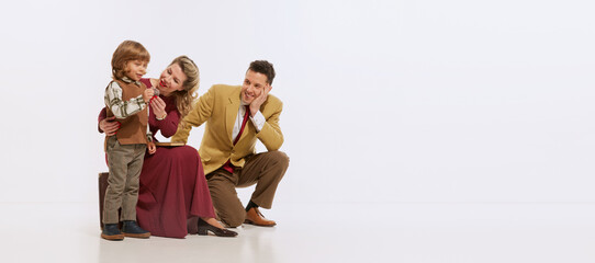 Portrait of young family, mother, father and little son in retro style clothes isolated over white background. Concept of retro style, 60s, 70s, family.