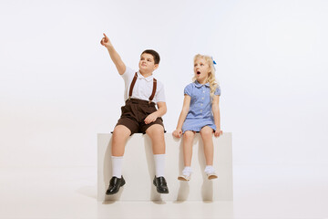 Naklejka premium Cute children, kids playing, having fun, talking together isolated over white background. Concept of childhood, friendship, family, fun, active lifestyle, fashion