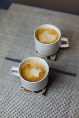 Two cups of coffee on a stand on the table