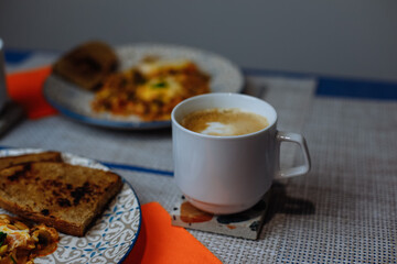 Breakfast, scrambled eggs with toast and coffee in a white cup