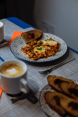 Breakfast, scrambled eggs with toast and coffee in a white cup