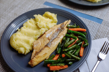 Potatoes with fish and sauce and vegetables on the table