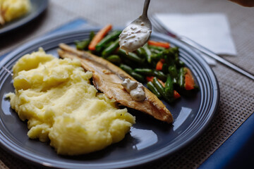 Potatoes with fish and sauce and vegetables on the table