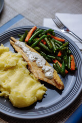 Potatoes with fish and sauce and vegetables on the table