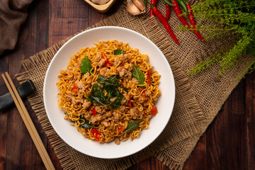 Spicy stir fried instant noodle with minced pork and holy basil leaves in white plate.Top view