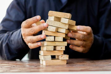 Business risk concept, business plan and business strategy. Insurance concept. Businessman holds the falling wood blocks