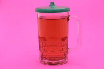 
glass of sweet tea with lid isolated on pink background