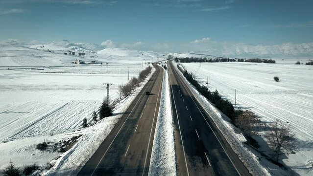 Aerial shot of a motorway and distant snow covered mountains in winter