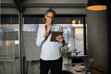Portrait of businessman in office. Man using digital tablet. Businessman having video call