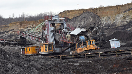 Fototapeta premium Bucket-wheel excavator during excavation at the surface mine. Huge excavator on open pit mine.