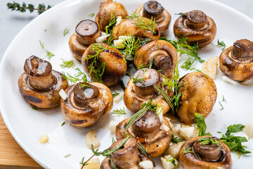 Yummy roasted mushrooms with garlic and herbs in a white plate, roasted mushrooms.
