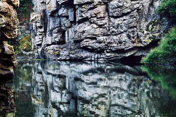 Deep rocky silver canyon with smoothly flowing water and reflection close up