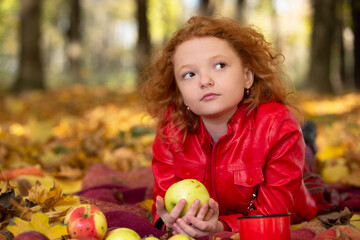 Fototapeta premium Sad red-haired girl with an apple in the autumn park.