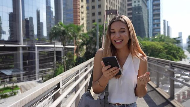 Excited business woman receving good news on smartphone outdoors