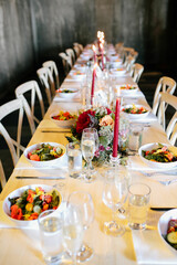 beautiful farm tables set for elegant summer wedding with flowers, salads and candles