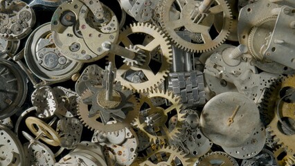 A pile of metal internal parts of an old clock. Dial, clockwork, bracelet, gears, cogwheels on black studio background. Disassembled clock mechanism of an old clock. Clock workshop. Close up.