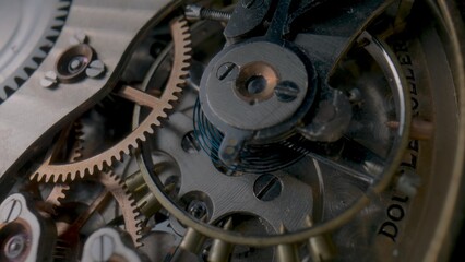 Antique pocket watch internal mechanism. Macro shot of clockwork of stopped clock with spring, gears, cogwheel and wheels with tootheds. Disassembled silver retro pocket watch inside. Clock workshop.