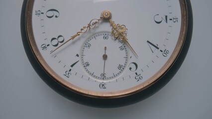 Antique pocket watch with a white dial and gold second, minute and hour hands on a light gray...