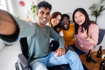 Inclusion and diversity concept with young indian man in wheelchair taking selfie portrait with...