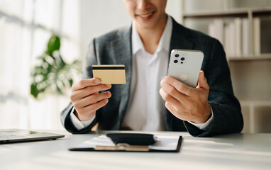 Businessman using smart phone for mobile payments online shopping,omni channel,sitting on table,virtual icons graphics interface screen in morning light.