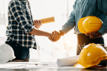 Construction team shake hands greeting start new project plan behind yellow helmet on desk in office center to consults about their building project.. - obrazy, fototapety, plakaty