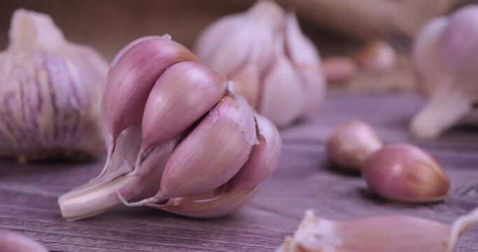 Fresh garlic with intense unique flavor and aroma on wooden background. One of the most popular ingredients of the basic recipes with nutritional properties and health benefits. Dolly shot 4k