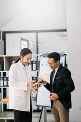 Fototapeta premium Kind leader executive manager share and discuss business solutions plan ideas on tablet with Asian female marketing manager in modern office.