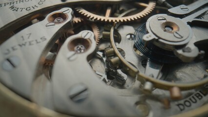 Internal vintage clockwork mechanism macro. Gold gears, metal gearing, wheels with tootheds. Disassembled watch with screws, cogwheels and winding spring. Open clockwork. Old pocket watch.