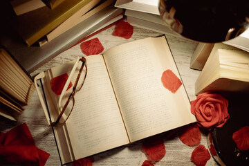 table with books, open book with glasses on top and rose petals