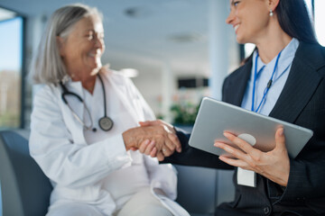 Young business woman shaking hand with elderly doctor.