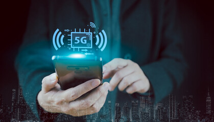 Hand holding a phone with a 5G hologram on the background of the city. The concept of 5G network, high-speed mobile Internet, new generation networks. Communication business technology, copy space.