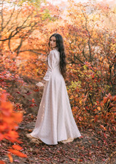 Obraz na płótnie Canvas Mystery art portrait fantasy woman queen walking in gothic autumn forest, white vintage style dress. Girl princess long wavy hair sexy lady looks back rear view. Red orange yellow color dark tree park