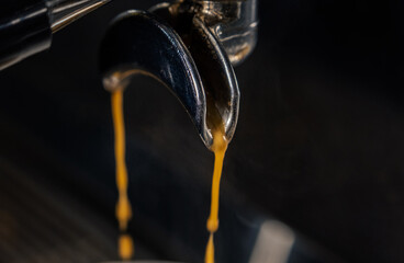 Espresso machine pours fresh black coffee closeup. Coffee machine preparing fresh coffee and pouring into yellow cups at restaurant, bar or pub.