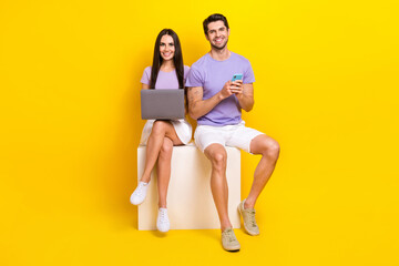 Full body photo of pretty young girl male sit white cube laptop gadget dressed stylish violet clothes isolated on yellow color background