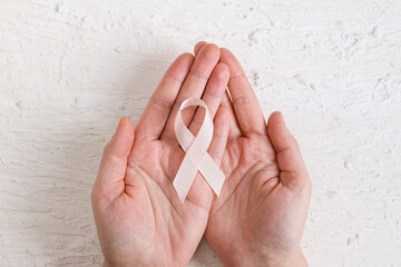 Adult hands holding Peach Ribbon. Uterine Cancer Awareness month. Healthcare and World cancer day...