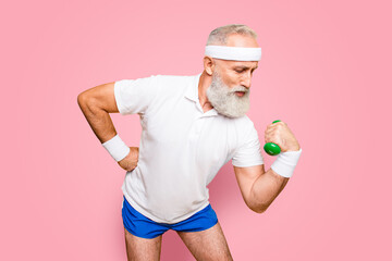 Naklejka premium Body care, hobby, weight loss lifestyle. Cool grandpa with confident grimace exercising holding equipment up, lifts it with strength and power, wearing blue sexy shorts, show legs