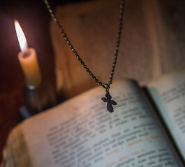 The cross hangs over a prayer book with a burning candle