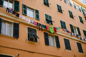 Fototapeta na wymiar Linen, clothes are dried on a rope, hanging on the facade of the building between the windows. Old Europe