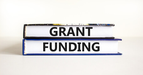 Grant funding symbol. Concept words Grant funding on books. Beautiful white table white background. Business and grant funding concept. Copy space.