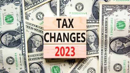 Tax changes 2023 symbol. Concept words Tax changes 2023 on wooden blocks on a beautiful background from dollar bills. Business Tax changes 2023 concept. Copy space.