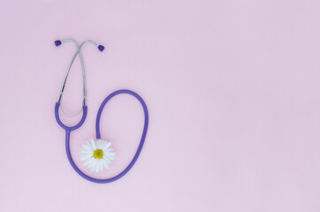 Stethoscope and white flower on pink background with copy space. Medical flat lay. International Nurse's Day.