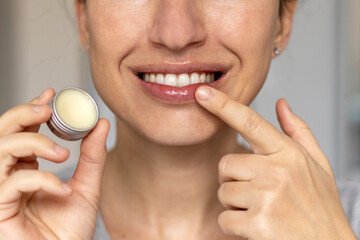 woman applying on lips balm or scrub from natural ingredients half bottom face kissing gesture...