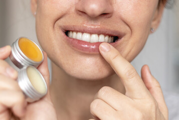 woman applying on lips balm or scrub from natural ingredients half bottom face kissing gesture...