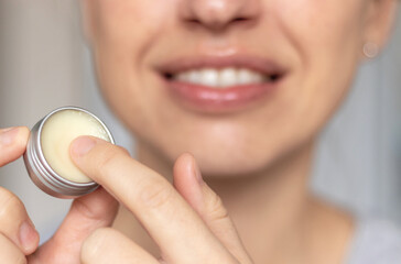 woman applying on lips balm or scrub from natural ingredients half bottom face kissing gesture smiling female.scrub and lip balm from small jars girl taking with finger rotation moves coconut oil