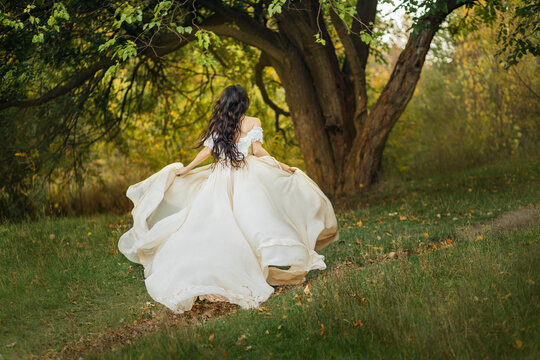 image art portrait fantasy woman in white vintage style dress. queen runs in summer forest. Girl princess long dark hair fly fluttering in wind mption. romantic lady back rear view. Green tree nature