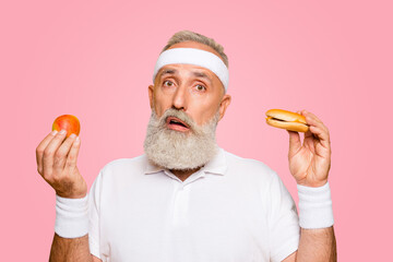 Athlete cool uncertain unsure ponder fit picky grandpa holds forbidden cheeseburger and fruit,...
