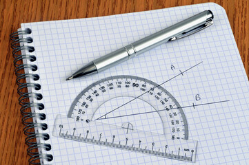 Mesure d'un angle avec un rapporteur et un stylo posés sur un cahier